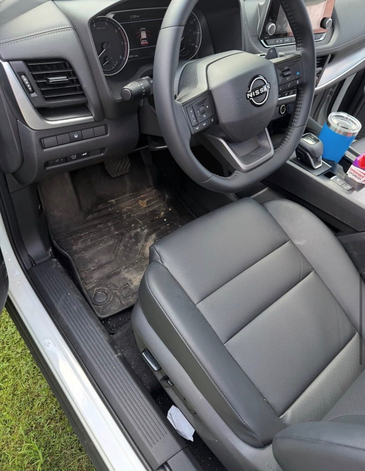 A driver's footwell before detailing, with dirt and debris ground into the floor mat